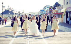 wedding party in purple and yellow walking on boardwalk