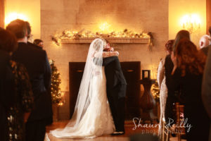 bride and groom kissing at fireplace